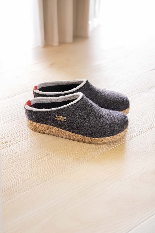 Pantofole in lana kris di haflinger appoggiate su pavimento di legno chiaro