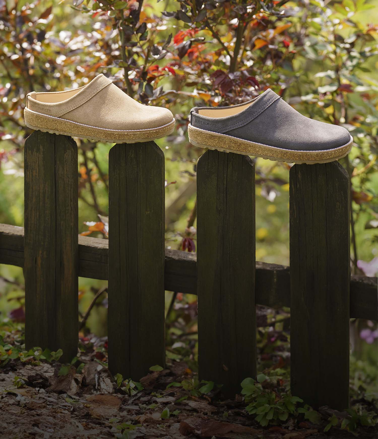 ciabatte sabot in pelle liscia haflinger travel marroni e nere appoggiate su staccionata in legno