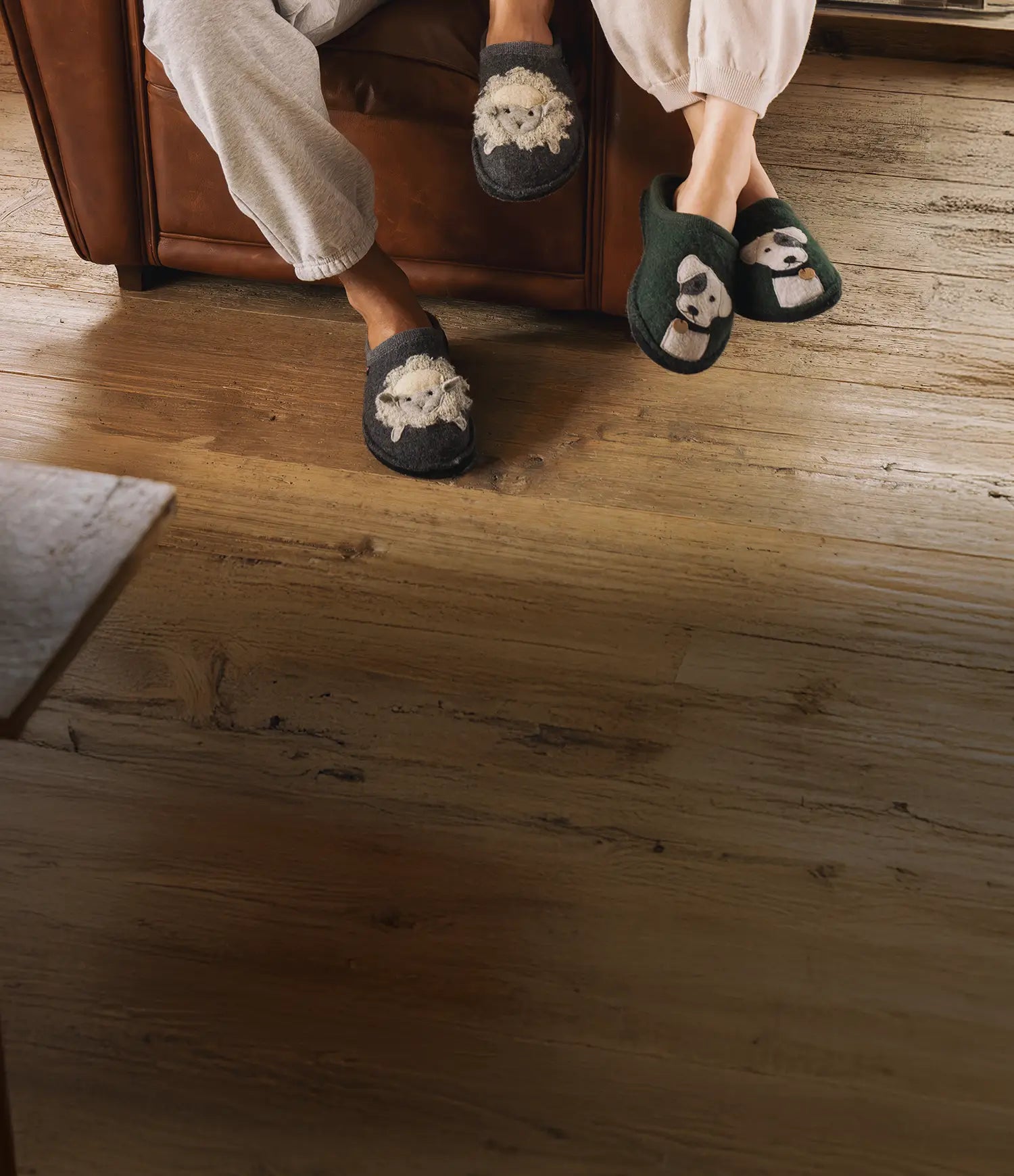 Due paia di pantofole haflinger in lana: un paio con decorazione pecora del modello lamby indossato da uomo e un paio con decorazione cane theo indossato da donna