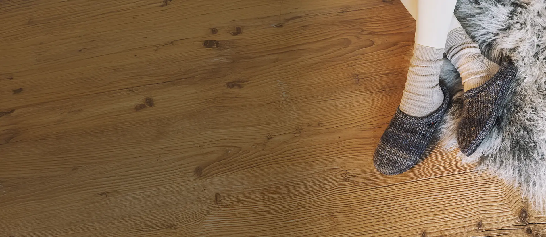 Primo piano dall'alto di pantofole lana tricotè color jeans indossate da donna sdraiata su tappeto