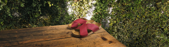 ciabatte a due fascie in pelle liscia haflinger bio mio rosse appoggiate su tavolo in legno