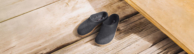 Primo piano di sabot haflinger di lana nere appoggiate su un pavimento di legno