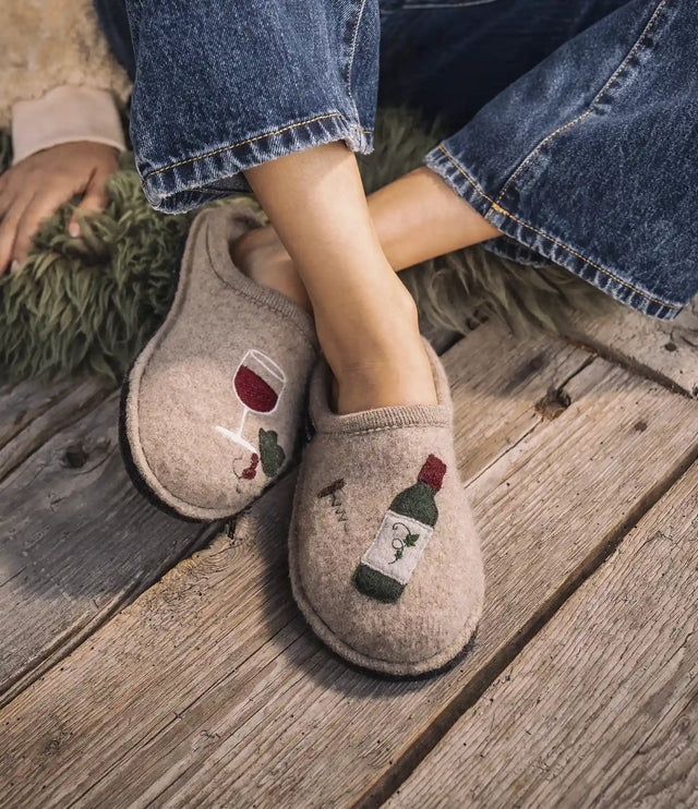 Primo piano di pantofole in lana haflinger con decori vino wine time indossate da una donna
