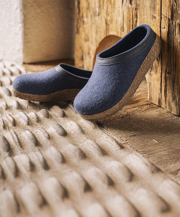 Primo piano con vista laterale di pantofole Torben Sabot Unisex jeans appoggiate su pavimento di legno