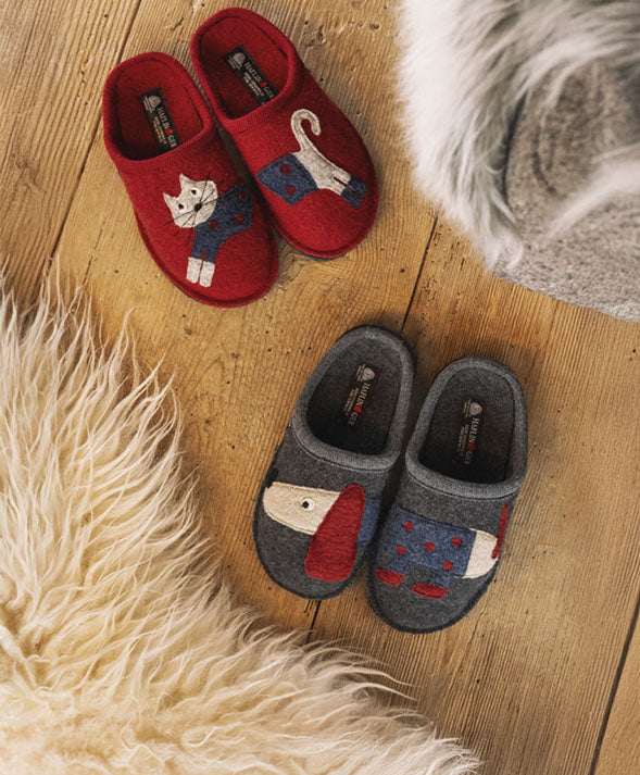 Ripresa dall'alto di Theo Sabot Unisex anthrazit e Cucho Sabot Donna paprika su pavimento di legno 