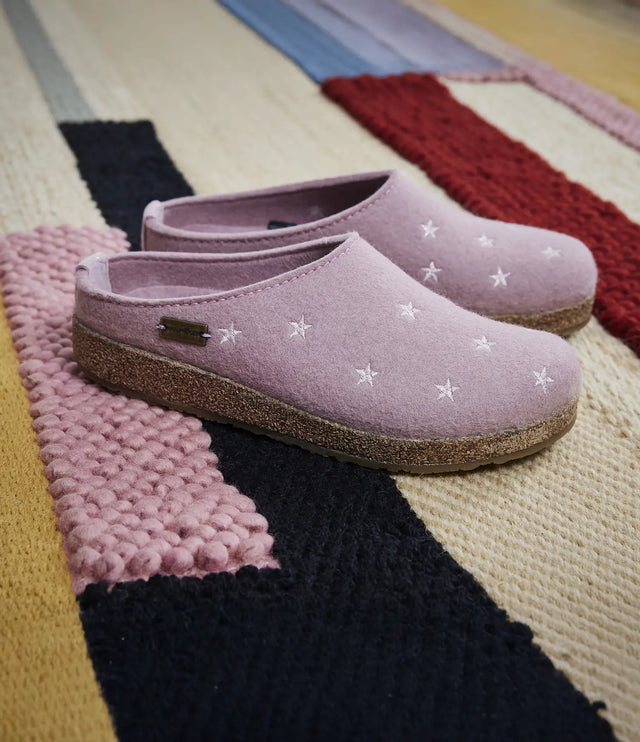 Primo piano di pantofole in lana stelline haflinger appoggiate su tappeto colorato
