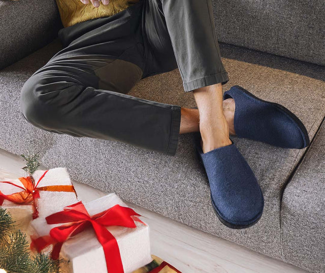 Primo piano di pantofole di lana blu indossate da uomo su divano